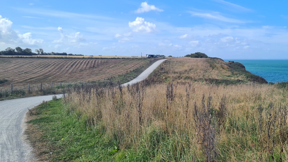 Cycle path between Omaha Beach and Pointe du Hoc running through coastal grassland with the sea alongside