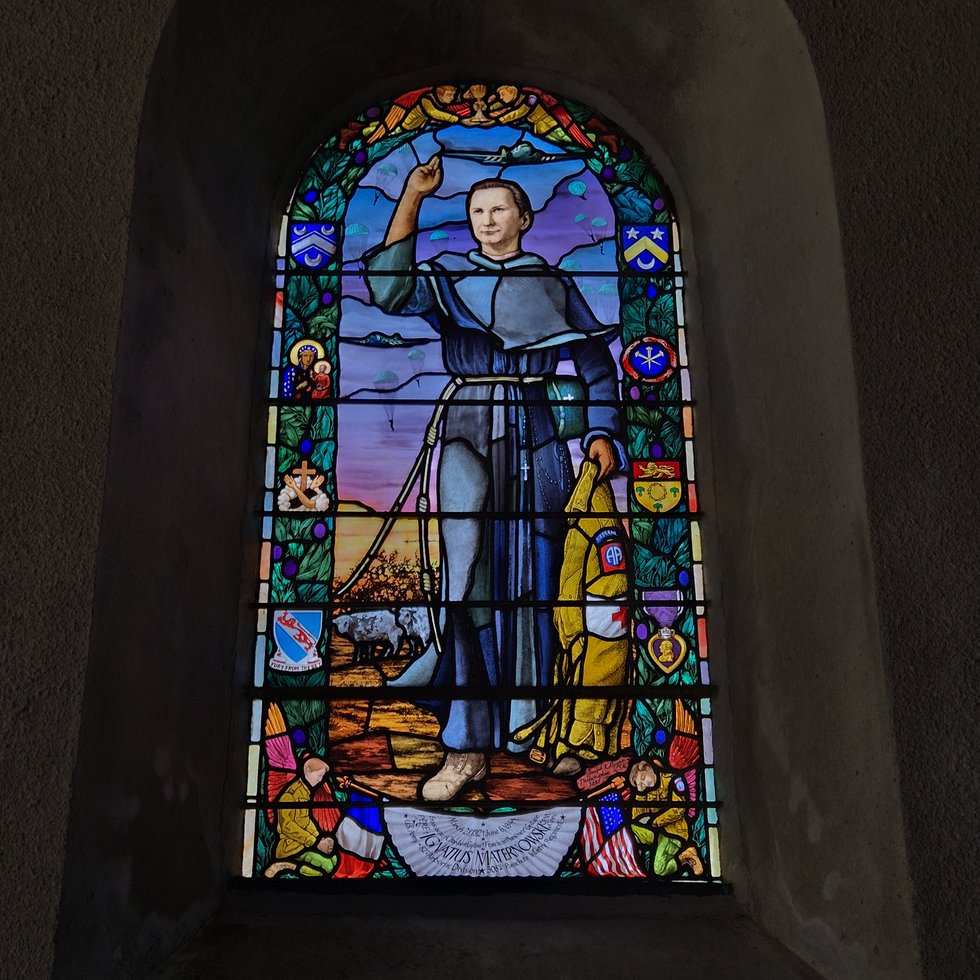 Interior of the church — the D-Day stained glass window showing St. Michael as a descending paratrooper